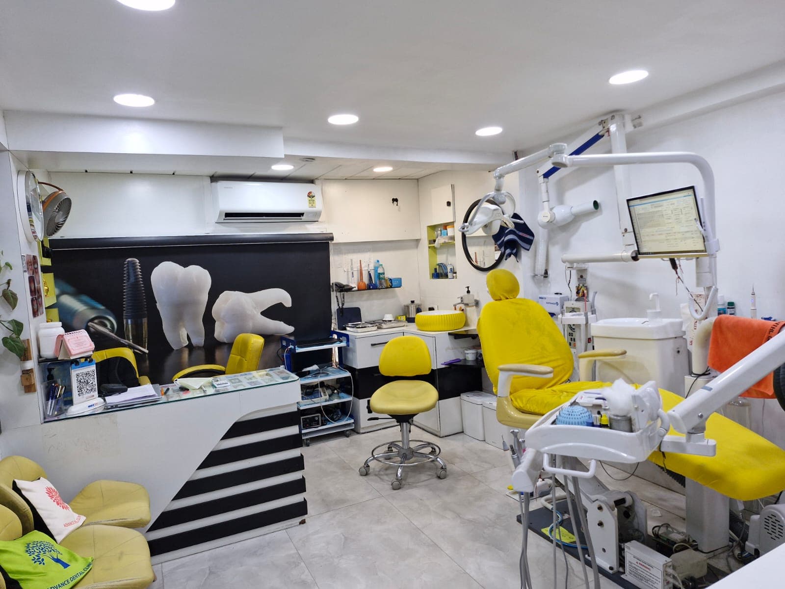 Modern dental clinic interior with a yellow chair, medical equipment, and large tooth mural.